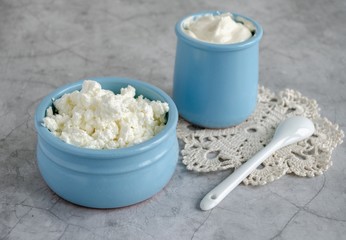 Cottage cheese, sour cream, milk in a blue bowl are on the table. Healthy breakfast.