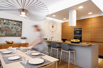 Interior of a kitchen and dining area with a girl setting the table