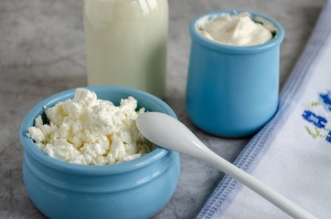 Cottage cheese, sour cream, milk in a blue bowl are on the table. Healthy breakfast.