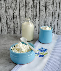 Cottage cheese, sour cream, milk in a blue bowl are on the table. Healthy breakfast.