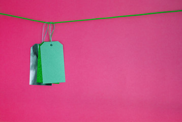 three colorful price tags on rope pink background