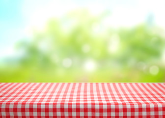 Checkered picnic red table cloth table on natural background. - obrazy, fototapety, plakaty