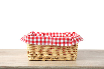 Straw basket decorated red checked picnic cloth on wooden background isolated