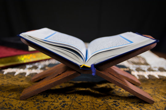Holy Book of Muslims Islamic Holy Book Quran Majid Closeup Shot with wooden Quran Stand and Prayer Rug Janamaz