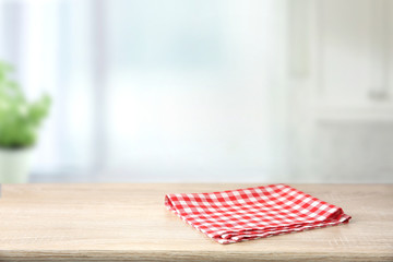 Red checkered folded picnic cloth on wooden table empty space background.