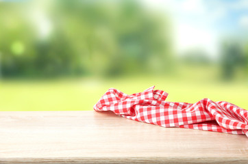 Red checkered picnic cloth on wooden table empty space background.