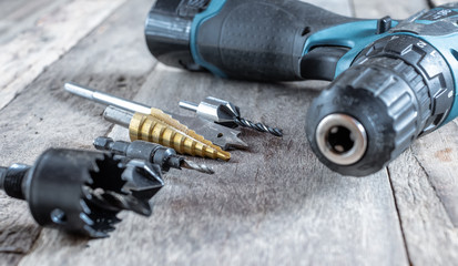 Variety of different types of bit drill with cordless drill displayed on old wooden background. Selective focus.