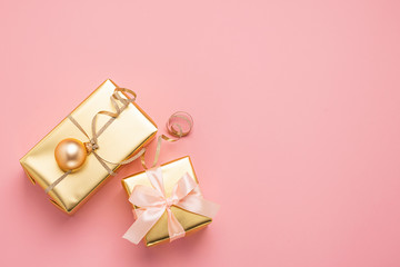 Festive boxes with satin ribbon bow golden toy balls a pastel pink background. Flat layout. Holiday concept. Copy space.
