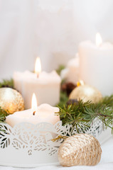 Christmas or New Year card. White burning candles on a light background. Golden balls and boxes with gifts.