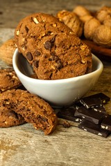 Homemade chocolate cookies with nuts on wooden table. Sweet food for coffee. Unhealthy food. Risk of obesity.