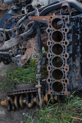 rusty disassembled cylinder block on the ground and in the background lies a rusty crankshaft