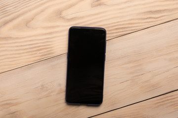Smart phone with black screen on wooden background with copy space