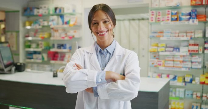 Portrait of an young female pharmacist consultant is smiling in camera in a drug store.
