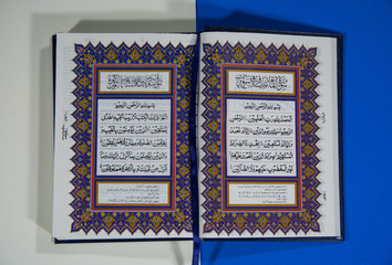 Top angle shot of Holy Quran with Arabic Text on white and Blue background