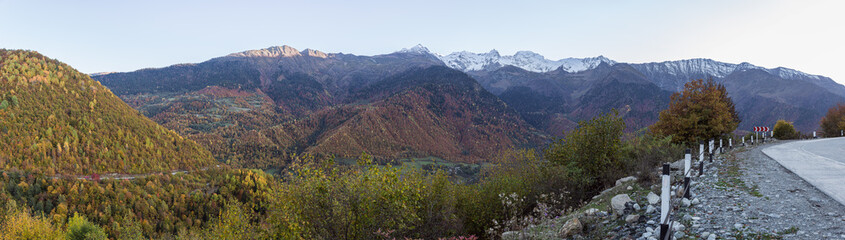 Panoramic  view of a mountain road passing through mountains and peaks in the snow, visible in the distance, in the mountainous part of Georgia - Svaneti at sunset