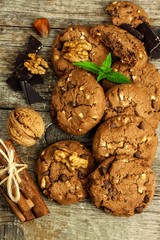 Homemade chocolate cookies with nuts on wooden table. Sweet food for coffee. Unhealthy food. Risk of obesity.