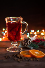 Hot christmas drink with spices on a dark background. Orange slices, spruce branch, bokeh in the...