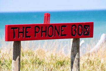Sign of a miniature phone box by the beach