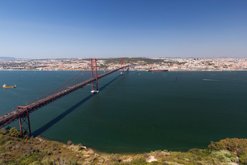 Fototapeta na wymiar Lisbon, 25 de Abril Bridge (Ponte 25 de Abril, 25th of April Bridge) and Tagus River in Portugal viewed from above on a sunny day in the summer.