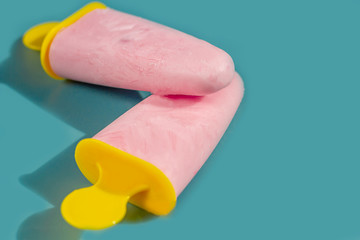 Homemade pink ice cream on a blue background. Natural fruit and berry popsicle  without sugar on a hot summer day. Flat lay, top view, copy space for text