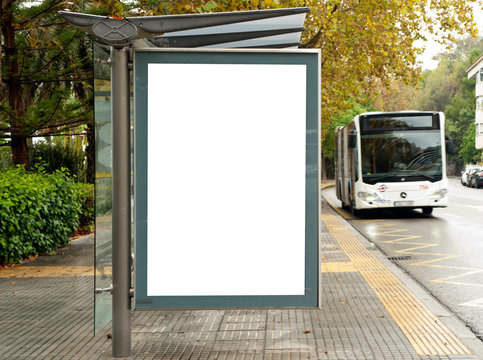 White blank vertical billboard at the bus stop on the city street. In the background of buses and roads. Sketch. Poster on the street next to the road.