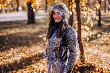 Happy woman in fashionable transparent raincoat outdoor in autumn