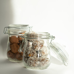 Energy balls in a jar with a yoke lock. Two containers with different dishes. Sharp shadows in daylight
