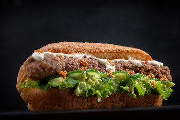 close up of kebab sandwich on black wooden background