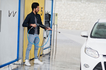 South asian man or indian male washing his white transportation on car wash.