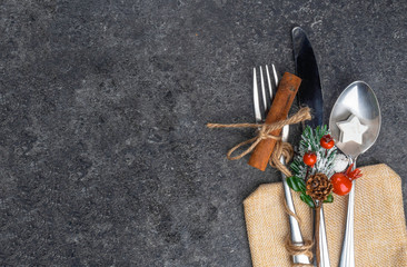 Christmas table place setting, cutlery in burlap bag with festive decorations star, cinnamon stick,...