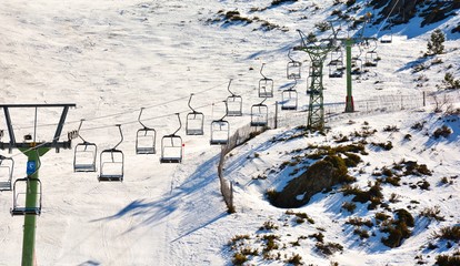 People in a ski lift and skiing at a ski resort with mountains full of snow