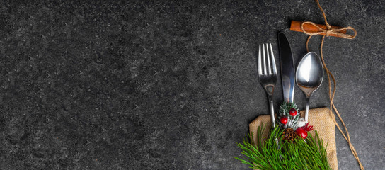Christmas table place setting, cutlery in burlap bag with festive decorations star golden bow,...