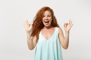 Young excited funny redhead woman girl in casual light clothes posing isolated on white background studio portrait. People lifestyle concept. Mock up copy space. Showing OK gesture keeping mouth open.