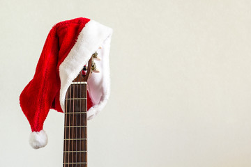 acoustic guitar with red Santa hat. Christmas song music concept on white background