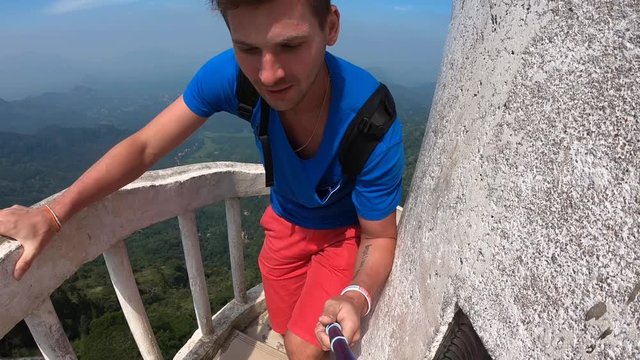 The traveler blogger makes videos for instagram on social networks. He make a dangerous climb to a unique tower 48 meters high located on the Ambuluwawa hill at an altitude of 356 m above sea level.