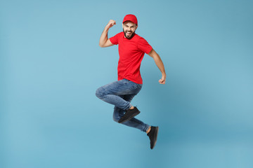 Fototapeta na wymiar Delivery man in red uniform workwear isolated on blue wall background, studio portrait. Professional male employee in cap t-shirt print working as courier dealer. Service concept. Mock up copy space.