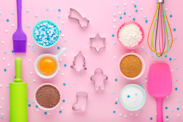 ingredients for baking and kitchen tools with cookie cutter on pastel pink background, flat lay