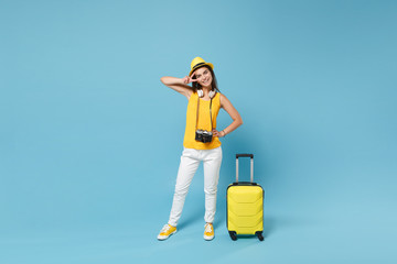 Traveler tourist woman in yellow casual clothes, hat with suitcase photo camera isolated on blue background. Female passenger traveling abroad to travel on weekends getaway. Air flight journey concept