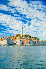 Fototapeta na wymiar Beautiful town of Rovinj on seaside in Istria, Croatia. Old historic houses and cathedral tower bell on the peninsula on Adriatic sea coastline.