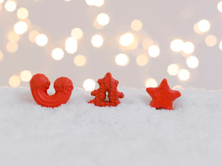 colorful christmas cookies on white snow with many small, shining lights in the background