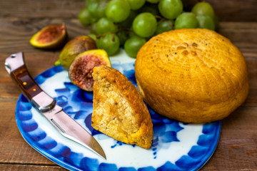 cheese, figs, grapes and knife on cutting board