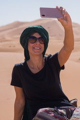 Girl taking a selfie in the desert with a turban on her head.