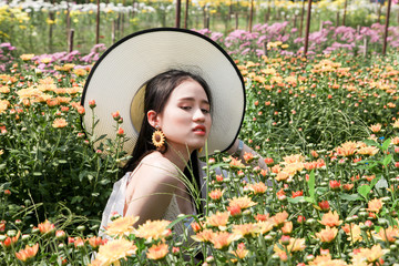 Portrait young beautiful asian woman in white dress relaxing at chrysanthemum flower garden