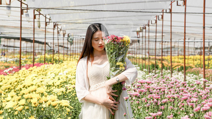 Portrait young beautiful asian woman in white dress relaxing at chrysanthemum flower garden