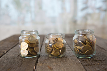 Glass jars with money coins ruble on wooden table