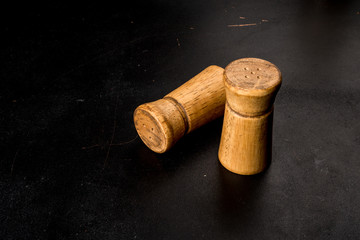 Salt and pepper in wooden salt shakers on a black background