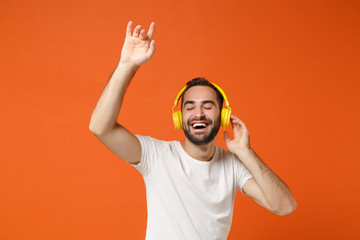 Cheerful young man in casual white t-shirt posing isolated on orange background in studio. People...