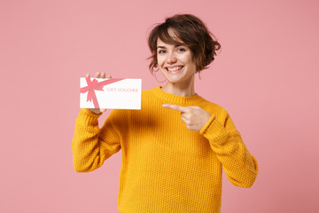 Smiling young brunette woman girl in yellow sweater posing isolated on pastel pink background...