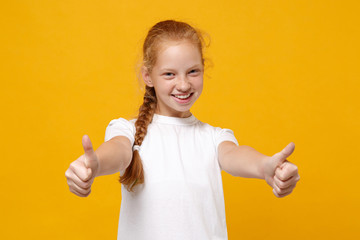 Smiling little ginger kid girl 12-13 years old wearing white t-shirt isolated on bright yellow background children studio portrait. Childhood lifestyle concept. Mock up copy space. Showing thumbs up.