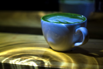 White ceramic cup with green matcha latte. Milk and shaved Japanese tea. Useful drink for health.